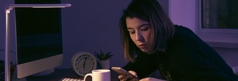 Illustration of a woman using her phone while jotting down notes on paper.